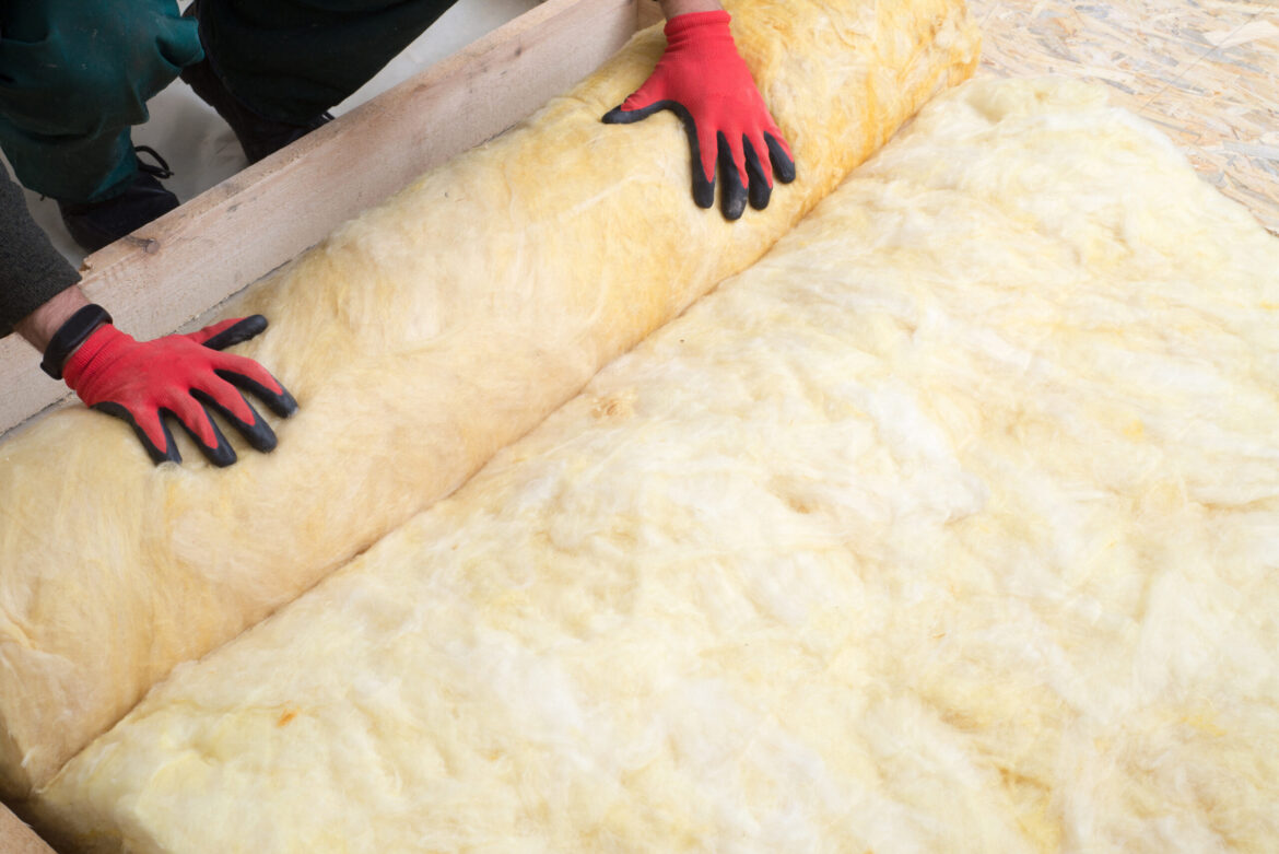 A homeowner lays insulation in attic