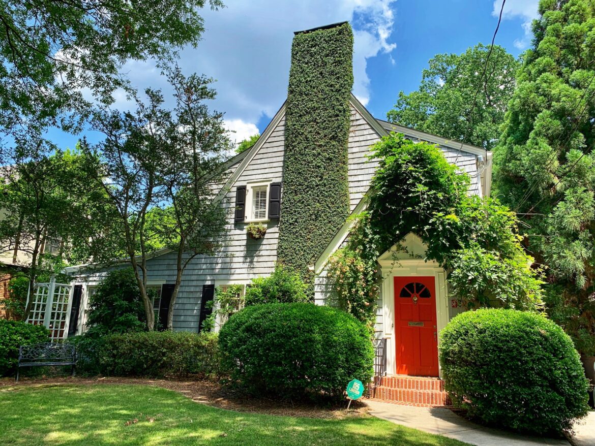 Two story home with red door and chimney, manicured lawn. Home repairs before you sell your home.