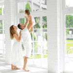 first-time homebuyer family in front of large windows.